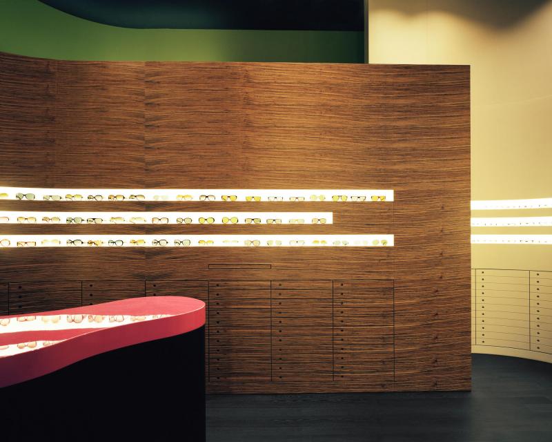 Müller Optik optician store eyewear display wall in ovangkol and counter in smoked oak and top in pink 
