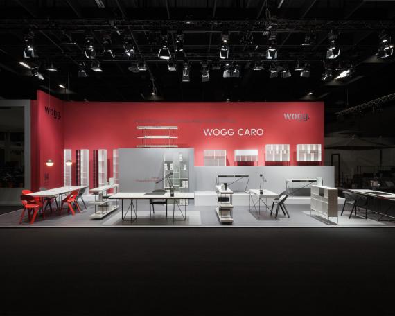 Furniture Fair Cologne 2016 general view Wogg Caro collection by Christophe Marchand displayed on cubic platforms in different shades of grey in front of a  red wall