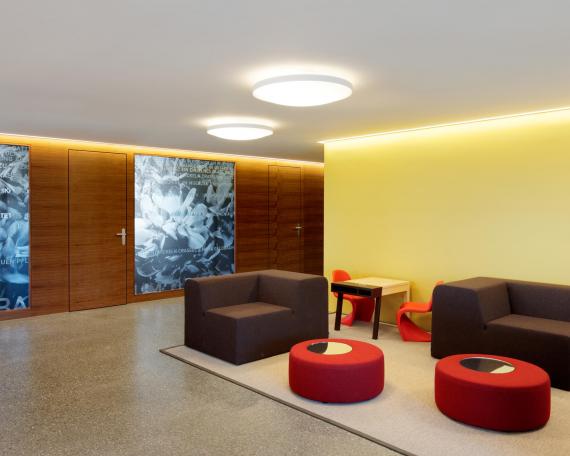 Raiffeisenbank Gommiswald waiting area with lounge chairs in front of a wall painted in yellow and the consulting rooms