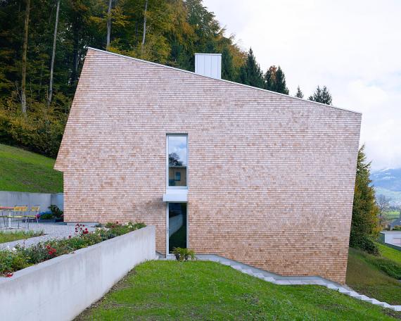 House Tuggen on the edge of the forest with wooden shingles in red cedar