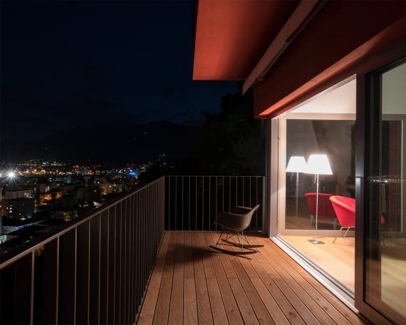 Umbau Ferienhaus Casa Sogno mio Locarno Blick vom Balkon durch die Hebeschiebetüren ins Wohnzimmer bei Nacht