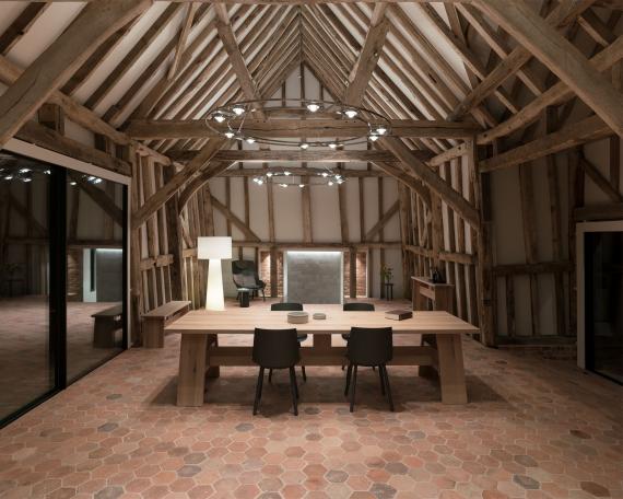 Conversion of barn at Chapel House Farm, Oakwood Hill, Surrey Long oak table from E15 on hexagonal terracotta tiles in front of restored half-timbered frame and Ocular chandelier from Licht im Raum 