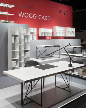 Furniture Fair Cologne 2016 Wogg Caro collection by Christophe Marchand exhibited on cubic platforms in different grey shades in front of a red painted wall 
