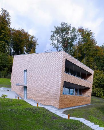 Haus Tuggen am Waldrand mit Schindelfassade und Loggia