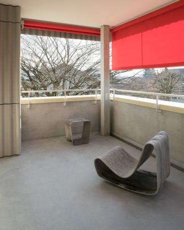 Conversion of apartment buildings on Baumgarten in Tann Detail of balcony with concrete floor and railing and textile sunshade in red
