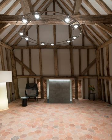 Umbau Scheune Chapel house farm in Oakwoodhill Surrey Innenraum mit Fachwerk und Boden mit hexagonalen Terrakottaplatten und Blick Richtung Treppenabgang vor Feinsteinzeugwand Mutina Mews Fog 