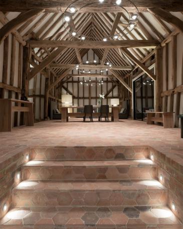 Umbau Scheune Chapel house farm in Oakwoodhill Surrey Innenraum mit Fachwerk und Boden mit hexagonalen Terrakottaplatten und beleuchteter Treppenabgang 