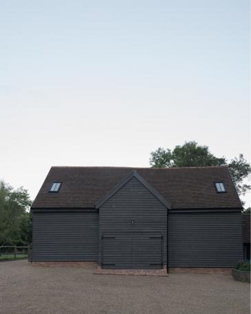 Conversion of barn at Chapel House Farm, Oakwood Hill, Surrey Barn with pre-weathered clapboard and closed doors 