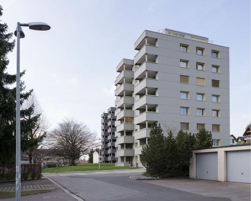 Conversion of apartment buildings on Baumgarten in Tann Balcony extension and new façade with corrugated Eternit Ondapress-36 sheets with open joints and horizontal bands 