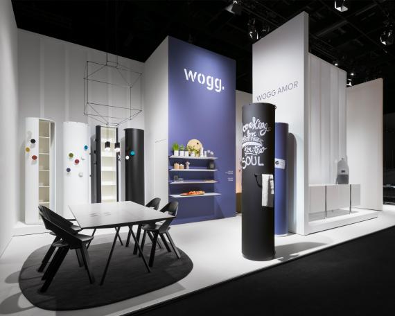 IMM Cologne 2017 Wogg Amor collection Advertising pillar in night blue NoStripe sideboard table Eichenberger stackable chairs Aluminium wall shelf against blue wall