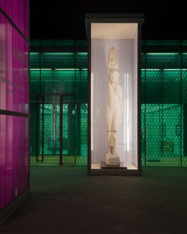 Osiris exhibition Museum Rietberg Enclosures in hot-dip galvanised steel and polycarbonate panels in violet, colossal statue of the queen Isis in front of the emerald building by night